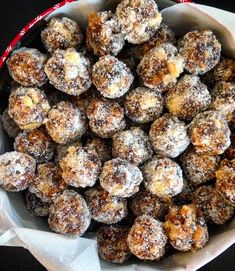 a bowl filled with powdered sugar covered donuts