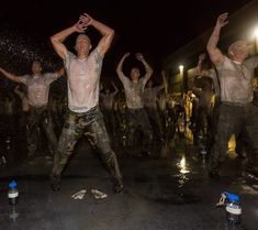 the men are dancing in the street with their hands up and arms raised as water is splashing on them