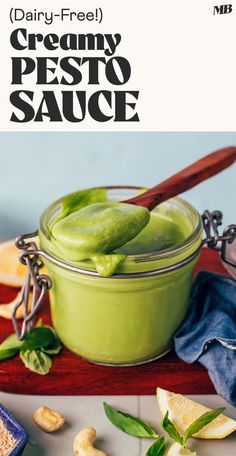 creamy pesto sauce in a glass jar with spoons and sliced lemons on the side