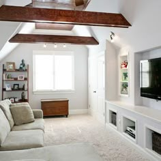 a living room filled with furniture and a flat screen tv on top of a wooden shelf