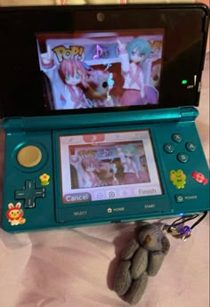 a nintendo wii game system sitting on top of a bed next to a stuffed animal