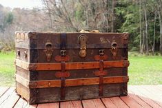 an old trunk sitting on top of a wooden table in front of some grass and trees