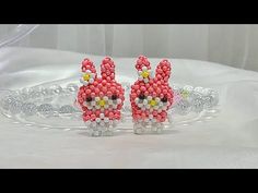 two pink and yellow beaded bunnies sitting on top of a table