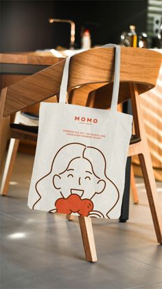 a tote bag sitting on top of a wooden chair in front of a table