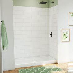 a white bathroom with green rugs and pictures on the wall next to the shower