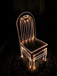 a lighted chair sitting on top of a black floor next to a rug and wall