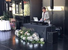 a man standing at a table with a laptop in front of him and surrounded by decorations