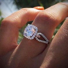 a woman's hand with a diamond ring on it and an orange flower in the background