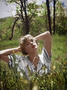 a woman laying in the grass with her hands behind her head