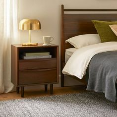 a bed with two nightstands and a lamp next to it on top of a rug