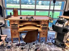 an office desk with lots of drawers in front of a large window, surrounded by various tools