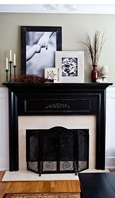 a living room with a fireplace and pictures on the mantel above it in front of a window