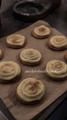 cookies with white frosting and cinnamon sprinkles are on a baking sheet