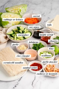 a table with many different types of food in bowls and on plates, including broccoli, cauliflower, cucumber, carrots, garlic, parsley, bread crumbs