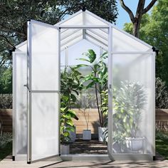 a small white greenhouse with plants in the corner and trees behind it on a sunny day