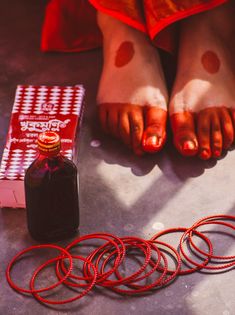 there is a bottle and some red rings on the floor next to it, with one person's bare feet in the background