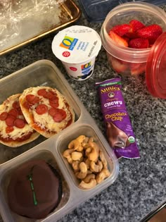 some food is sitting in plastic containers on a counter top next to fruit and yogurt