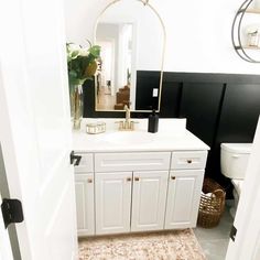 a white bathroom with black walls and gold accents on the sink, toilet and mirror