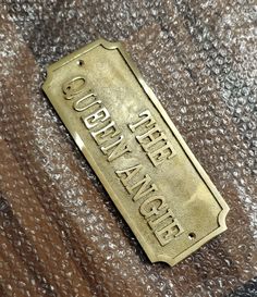 a close up of a gold colored metal sign on a carpeted surface with words written below it