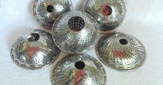 six metal bowls with holes in them on a white surface