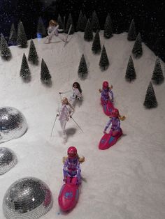 several toy skiers and snowboarders are in the middle of a snowy hill