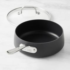 an empty pan with a lid on a marble counter top next to a frying pan