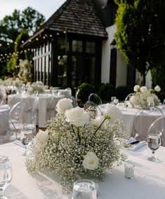 the table is set with white flowers and baby's breath in centerpieces