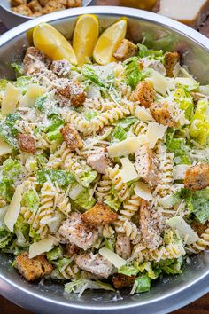 pasta salad with chicken and parmesan cheese in a silver bowl on a wooden table