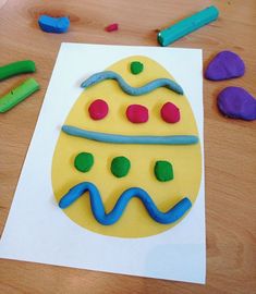 an egg shaped cake sitting on top of a table next to colored crayons