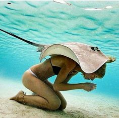 a woman kneeling down in the sand under water