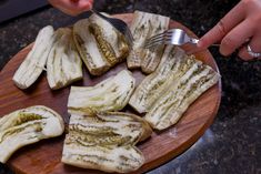 someone is cutting up slices of food on a wooden plate with a knife and fork