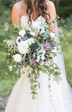 a bride holding a bouquet of white and purple flowers