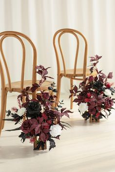 two wooden chairs with flowers in them sitting on the floor next to eachother