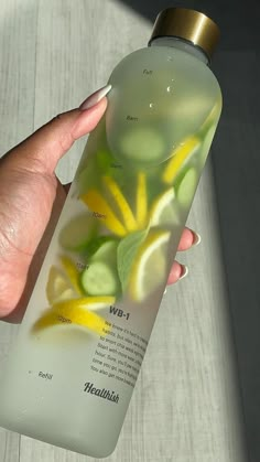 a hand holding a bottle with yellow and green flowers on it