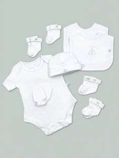 a baby's white outfit and booties are laying next to each other on a gray background