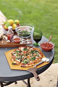 a pizza sitting on top of a wooden cutting board next to a table filled with food