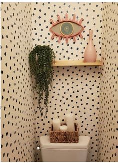 a white toilet sitting in a bathroom next to a wall mounted shelf with a potted plant