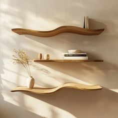 two wooden shelves with books and vases on them against a wall in the sunlight