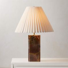 a lamp that is sitting on top of a white table next to a dresser with drawers