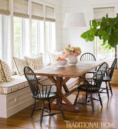 a dining room table with four chairs and a bench in front of the window,