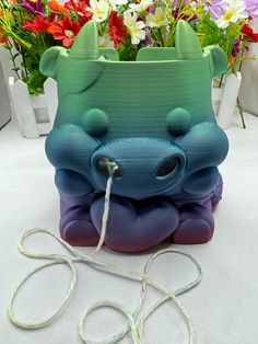 an animal shaped vase sitting on top of a white table next to some colorful flowers