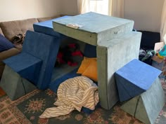 a room with blue and green furniture on the floor in front of a couch, rug and window