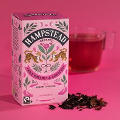 a box of tea next to a cup of tea on a pink background with the word hampstead