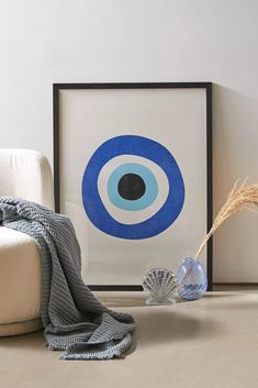 a blue and white art print with an eyeball on it next to a seashell