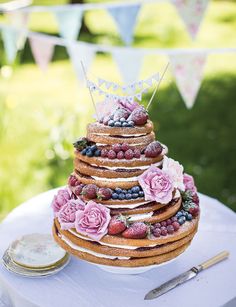 a wedding cake with fresh berries and blueberries on the top is sitting on a table