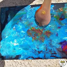 a person standing on top of a blue piece of art that has been painted with acrylic paint