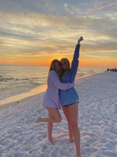 two women standing on the beach with their arms around each other