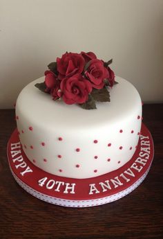 a white and red birthday cake with roses on top