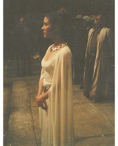 a woman in a white dress standing on a sidewalk with other people behind her and the caption bridal e