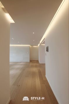 an empty room with white walls and wooden floors is lit by recessed lighting on the ceiling